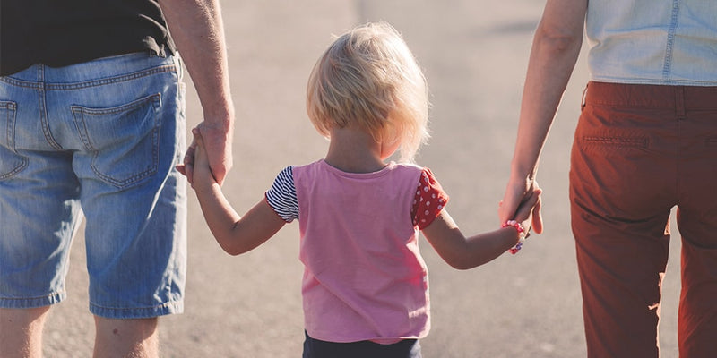 Petite fille qui tient la main de ses parents