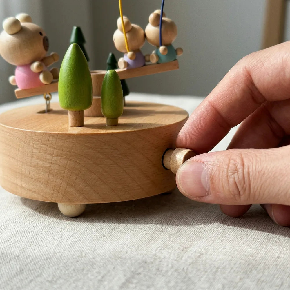 Gros plan d'une main tournant le remontoir en bois d'une boîte à musique bascule des oursons