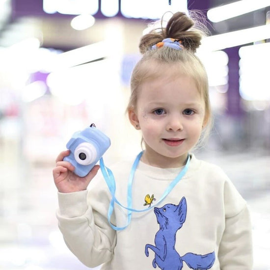 Une petite fille tenant un Appareil Photo Numérique Enfant dans un aéroport.